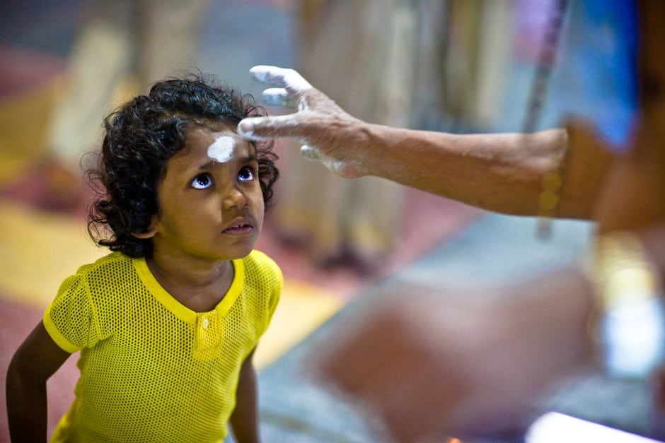 A child devotee of the Hindu god, Murugan receives a tilaka of ash from a priest, during Thaipusam. Penang, Malaysia