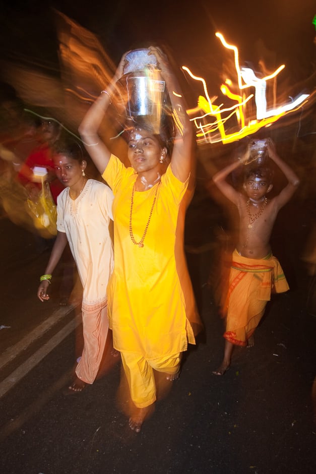 Devotee walk log distances with heave burdens, called kavadi. These are filled with milk and will be poured out over the idol once they reach the temple.