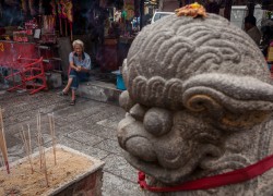 A man sits outside of the Goddess Of Mercy temple in George Town, Penang, Malaysia. Many of George Town's homeless or poor gather at this temple for handouts of food or small amounts of money.