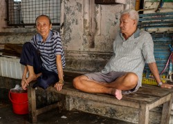 Two old friends sit and watch life go by at the Campbell Street market in Georgetown Penang.