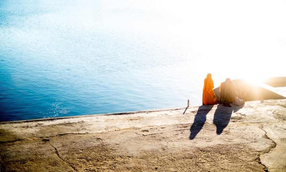The early morning sun shines on two women at the bathing ghats around Pushkar Lake.