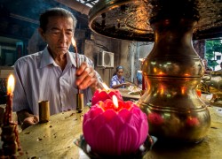 A Taoist man lights a candle at the Goddess of Mercy Temple in Georgetown, Penang, Malaysia. Does he care what I do with his image?